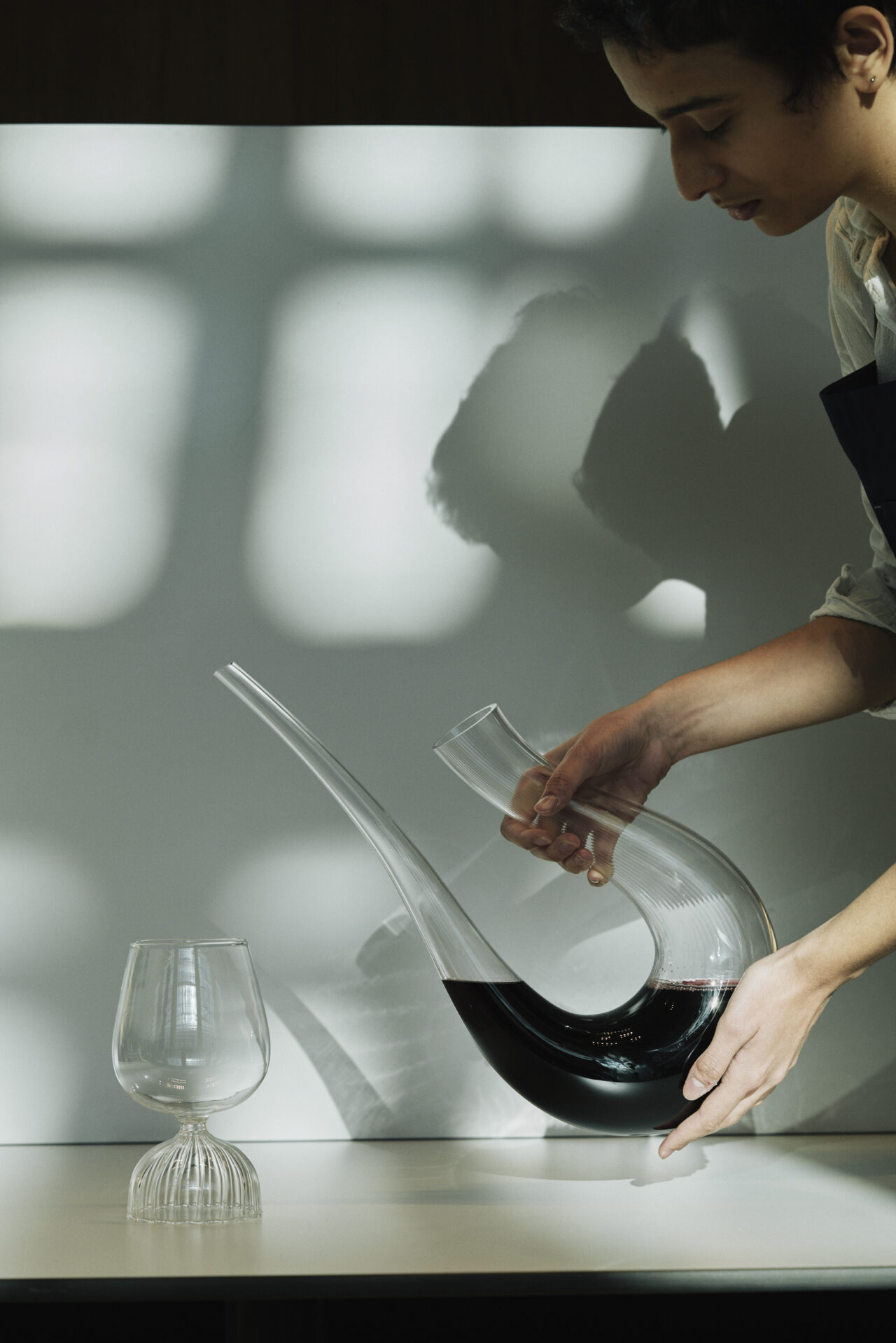 Eine Frau schenkt Wein aus einer Karaffe in ein Glas
